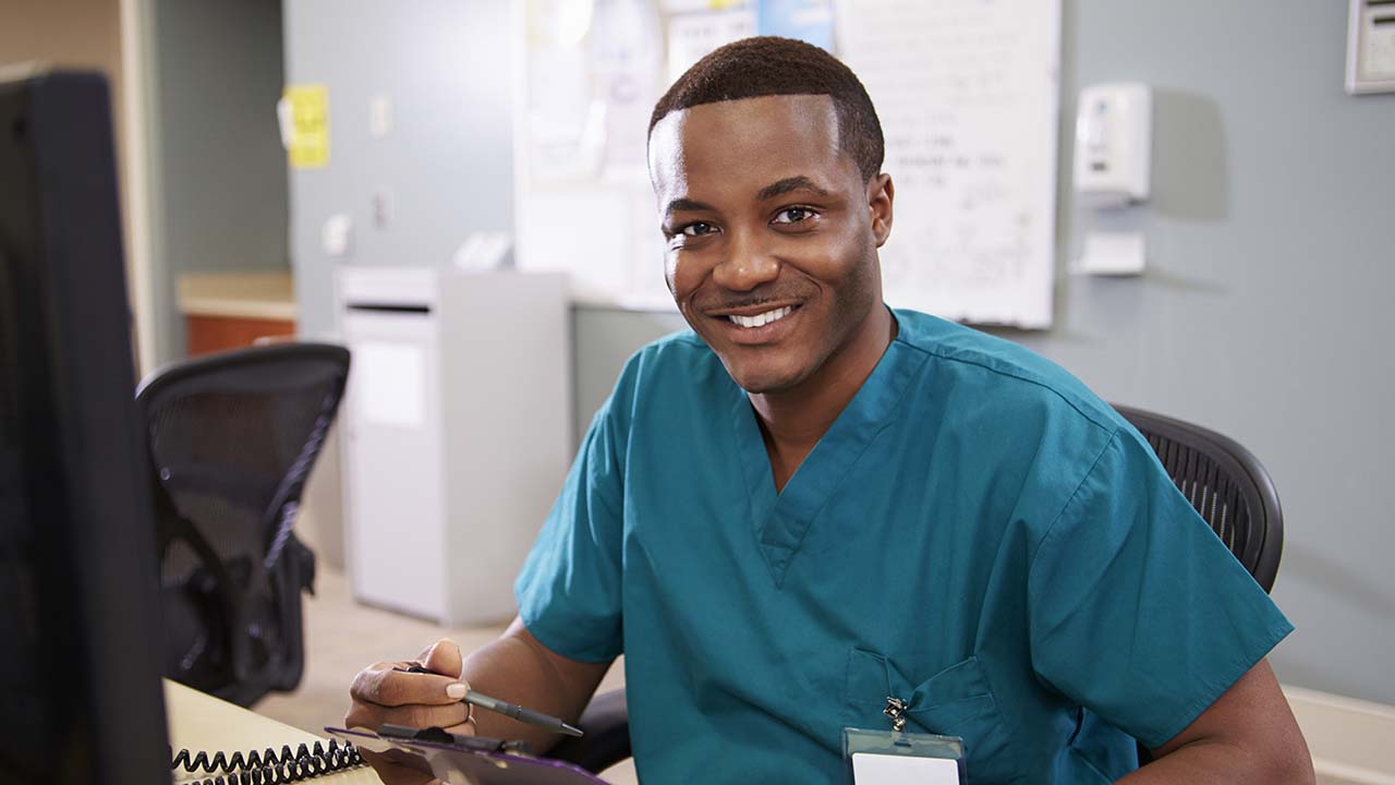 admin assistant smiling is sitting at computer doing data entry for the weight loss practice