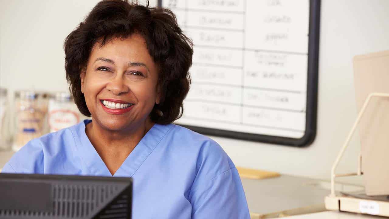 a woman in blue scrubs at the reception desk meets new patients at the weight loss clinic